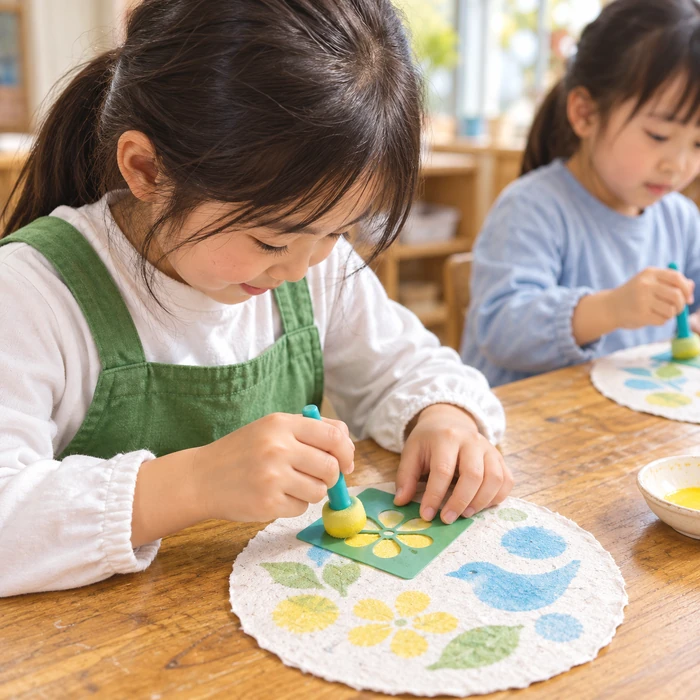 型とスポンジを使って丸い紙に色をのせる子どものイメージ